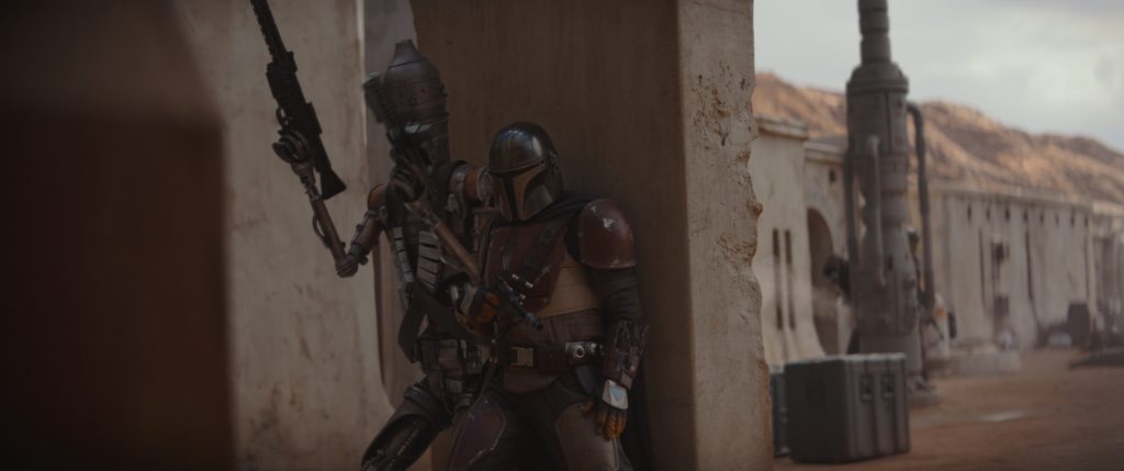 The Mandalorian and IG-11 taking cover as they fight their way to collect their bounty.