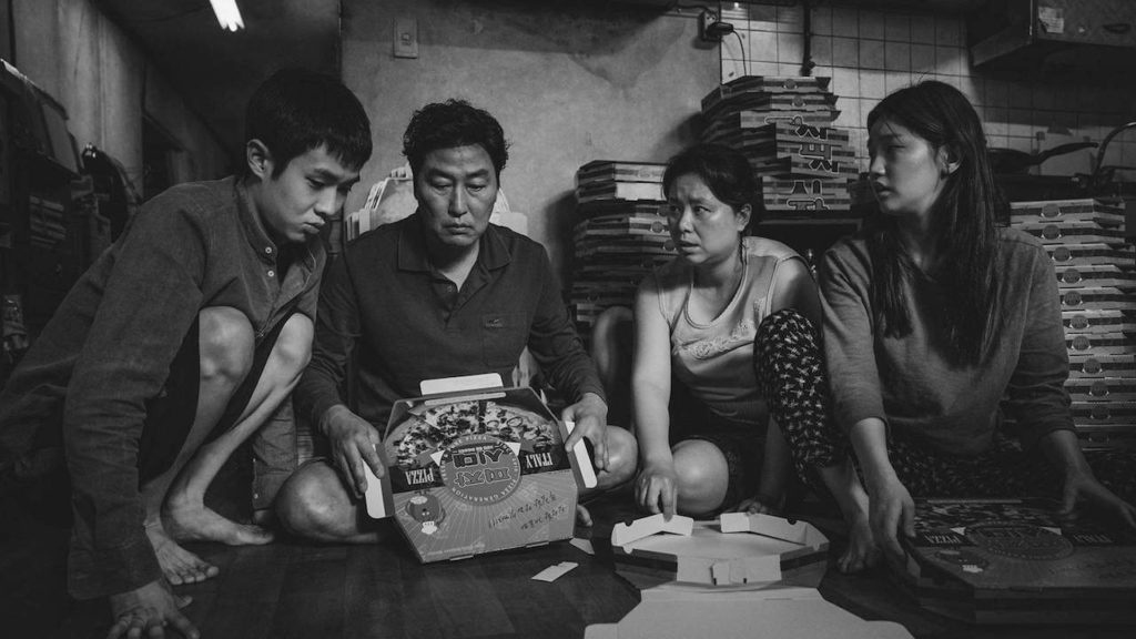 The Kim family constructing pizza boxes in the movie Parasite.