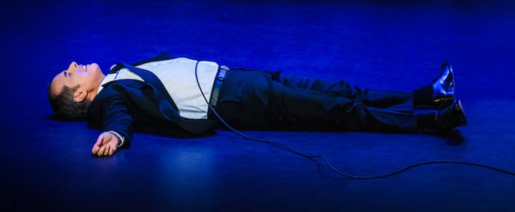 Jerry lying down on stage in his new stand-up special, Jerry Seinfeld: 23 Hours to Kill.