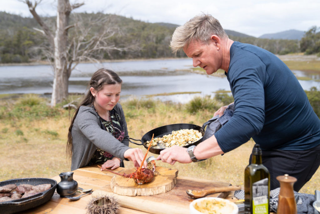Esther offers assistance while Gordon Ramsay prepares crayfish poached in sea urchin butter, finished with Tasmania’s own pepperberry and leatherwood honey during the big cook in Dunalley, Tasmania.