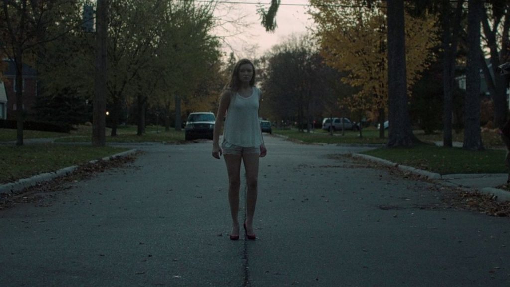 Annie waiting in the middle of the street in It Follows.